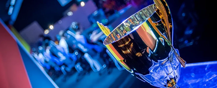 Gouden kampioenstrofee op een tafel tijdens een e-sporttoernooi met onscherpe spelers op de achtergrond.